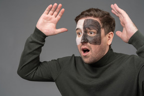 Three-quarter view of an astonished male football fan raising hands