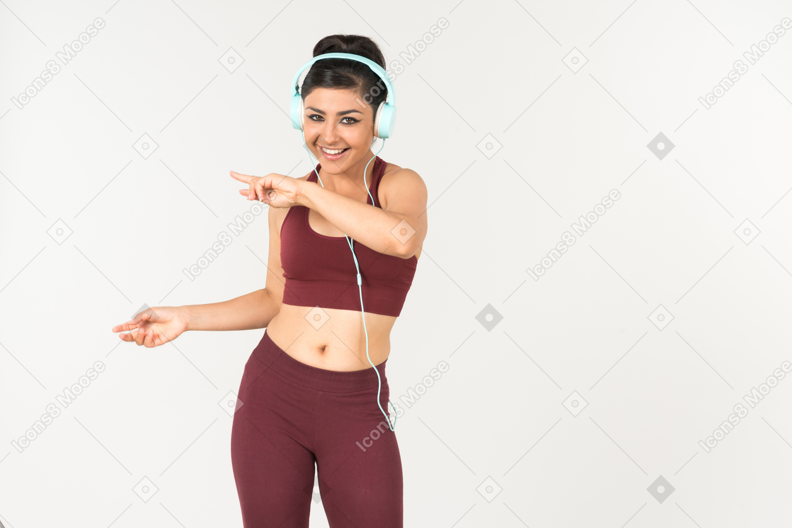 Laughing young indian woman in sporstwear listening to music in headphones