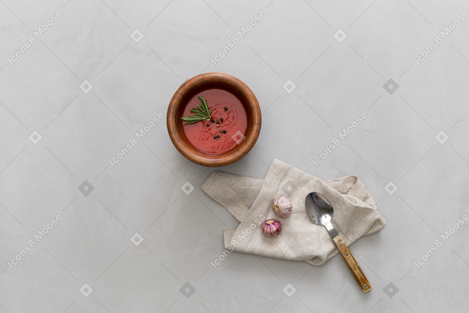 A bowl of gazpacho, some garlic and a spoon