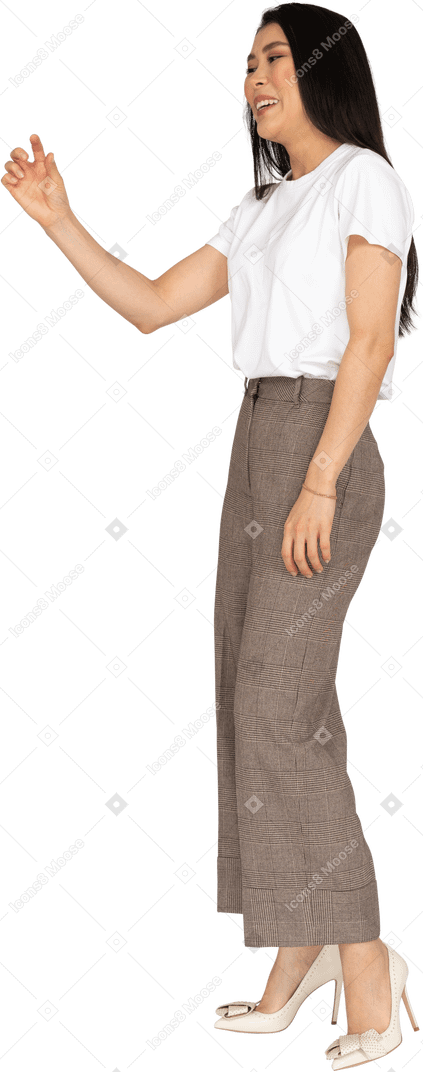Vista di tre quarti di una giovane donna in calzoni e maglietta bianca che mostra una dimensione di qualcosa