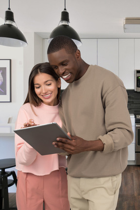 A man and woman looking at a tablet in a kitchen