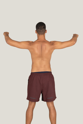 A backside view of the strong sunburnt man holding his hands up