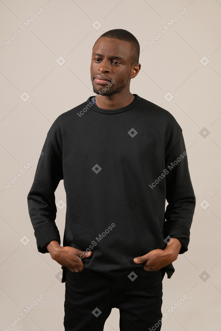 Young man looking aside with hands in pockets