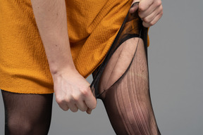 Cropped photo of a person in orange dress ripping tights