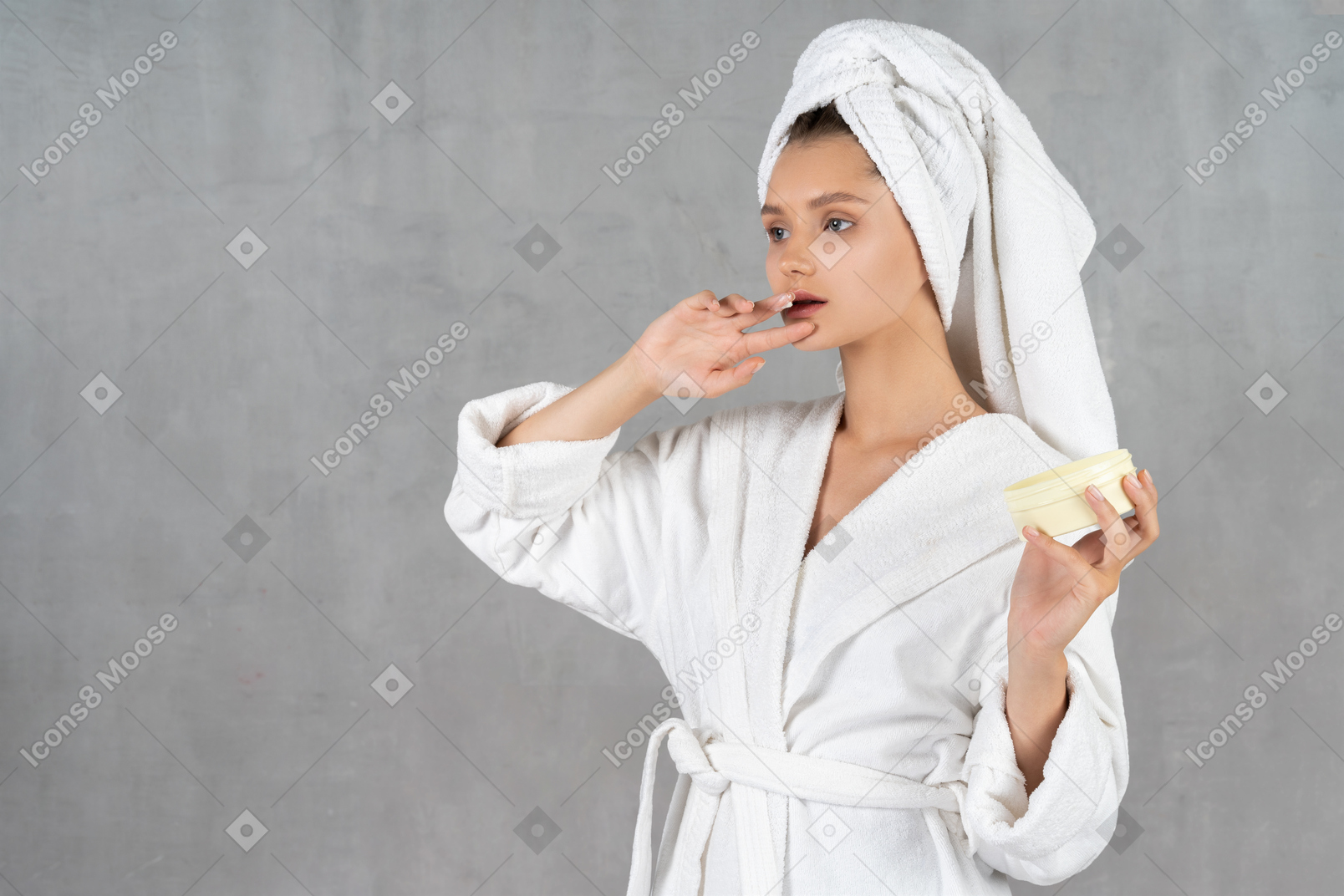 Woman in bathrobe touching her lip and holding tub of cream