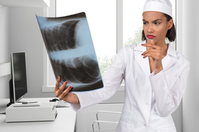 A woman in a white lab coat holding a x - ray