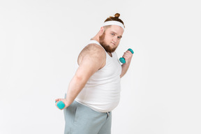 Serious looking big guy in sportswear lifting hand weights