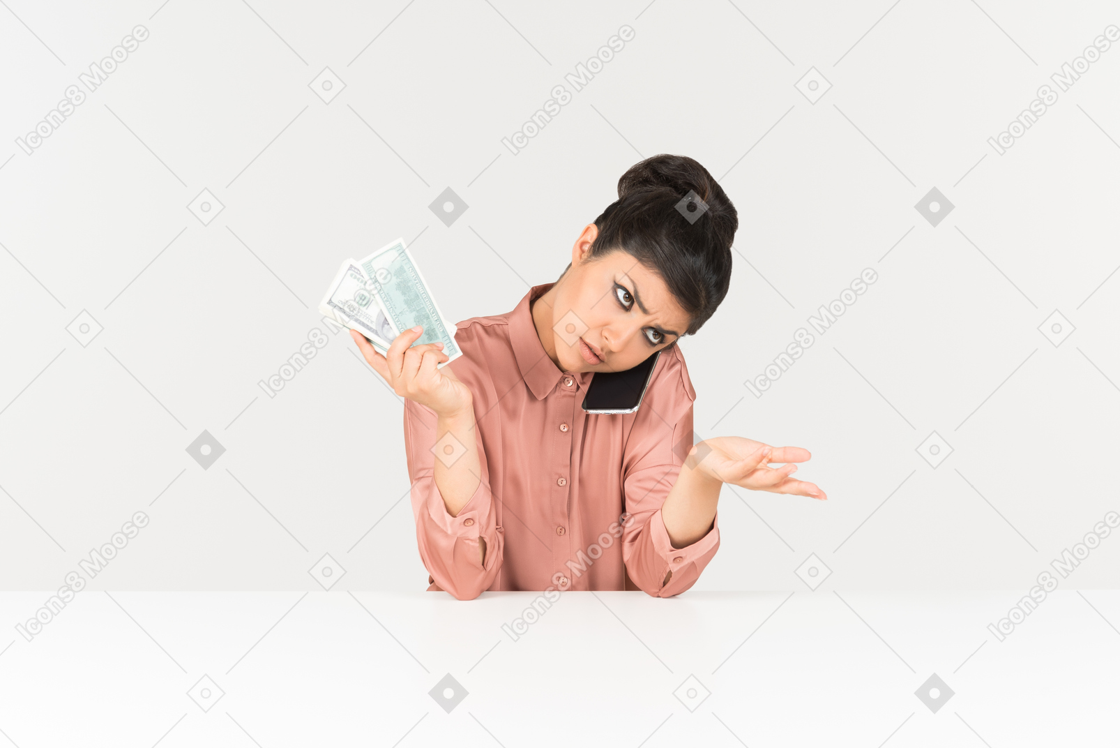 Troubled looking young indian woman holding money bills and talking on the phone
