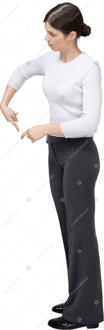 Vista lateral de una mujer en ropa casual apuntando hacia abajo con un dedo