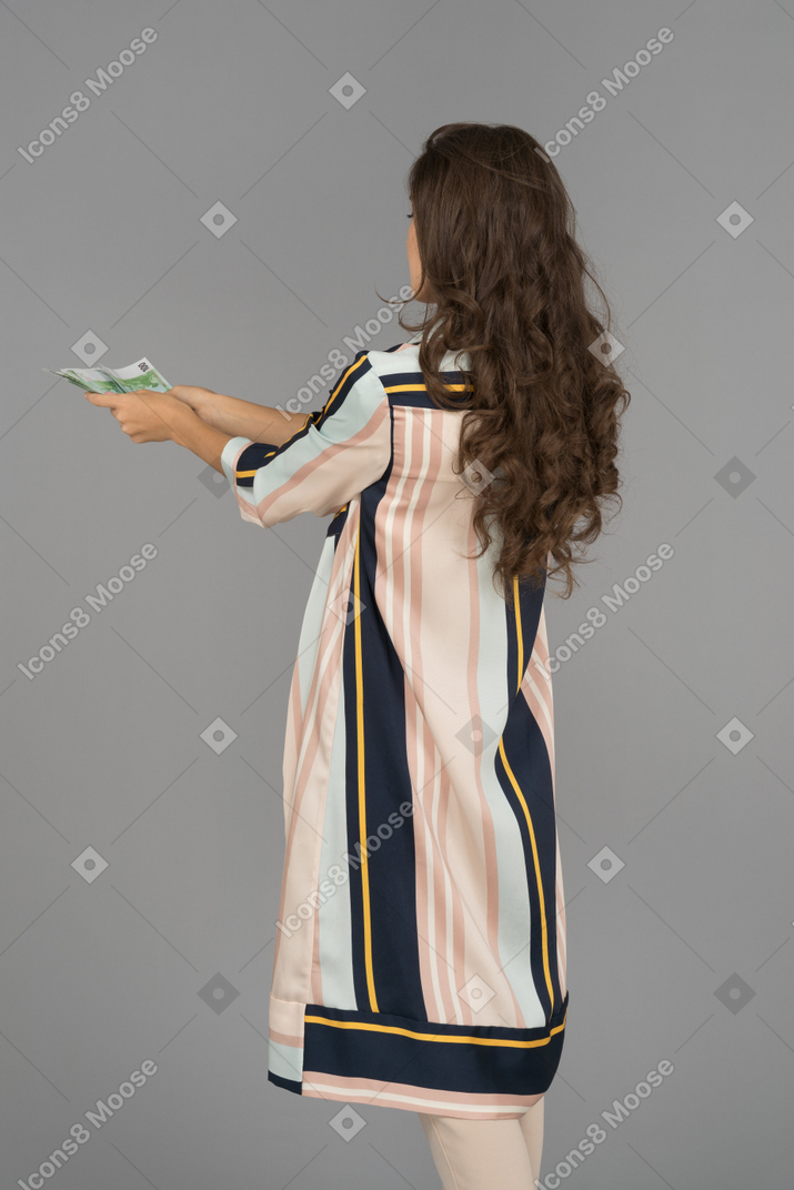 Long haired brunette woman outstretching hands with cash back to camera