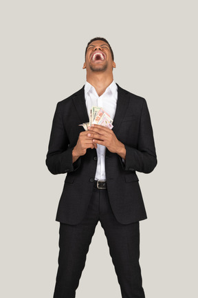 Вид спереди молодого человека в черном костюме, держащего банкноты