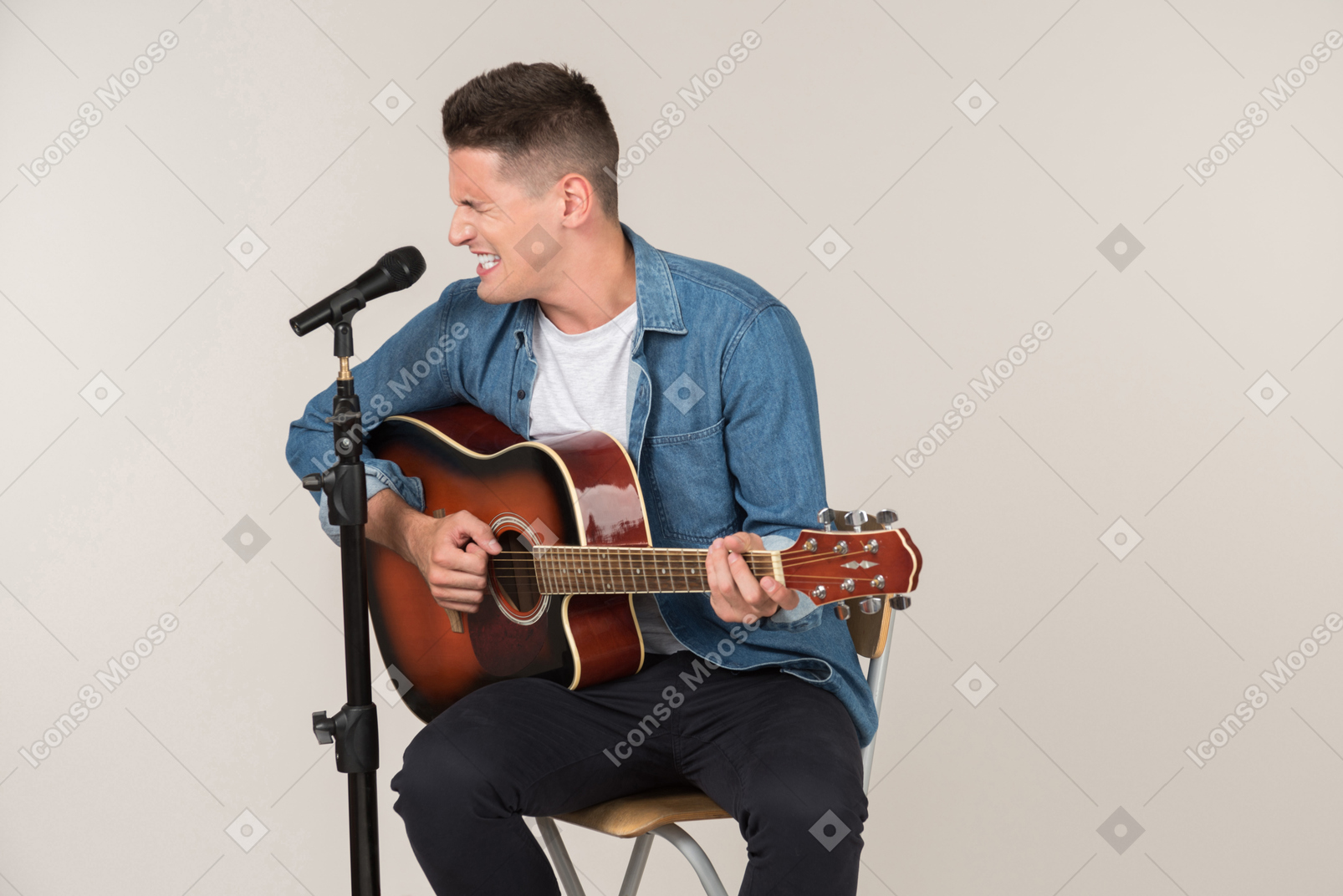Laughing young guy singing and playing on a guitar