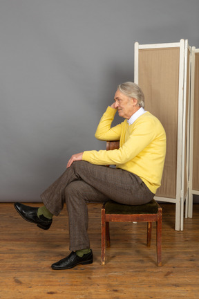 Seitenansicht eines mannes mittleren alters, der auf einem stuhl sitzt