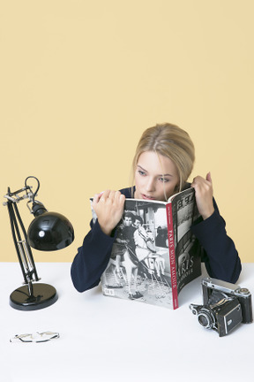 Young woman holding a magazine and looking distracted