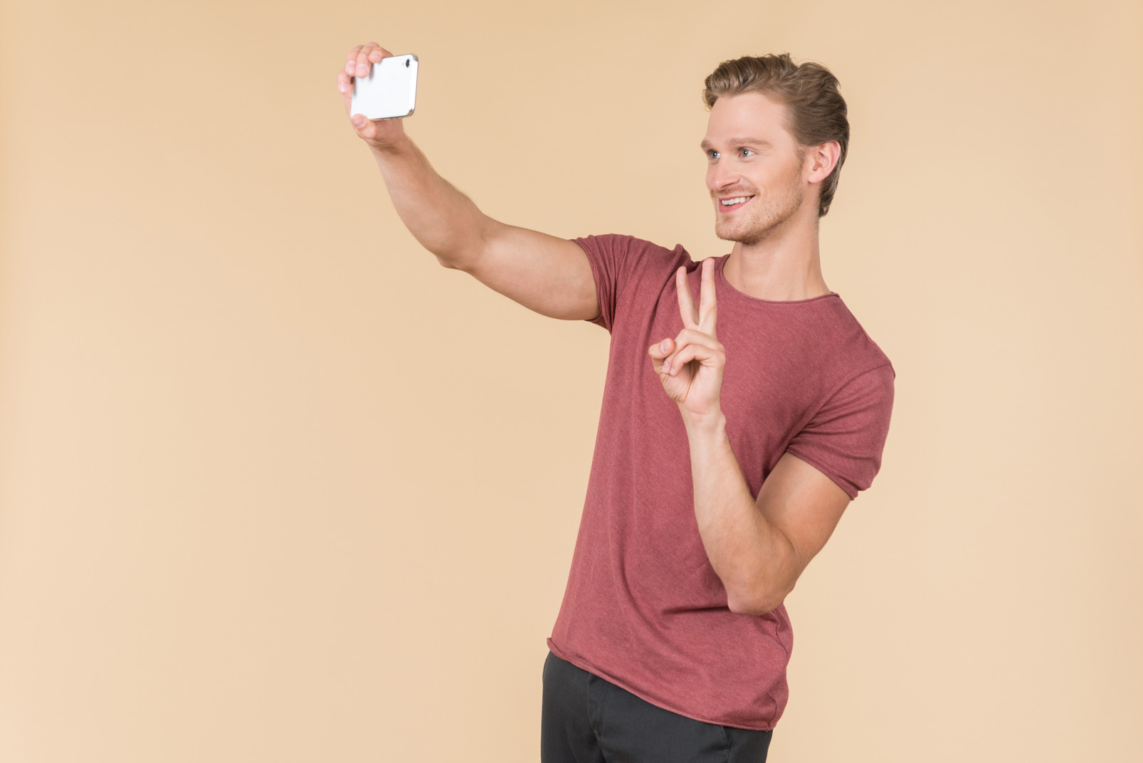 Young guy showing victory sign and making a selfie