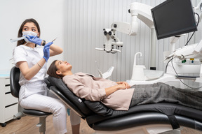 A figura intera di un dentista femminile disturbato e del suo paziente con uno specchio