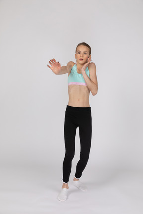 Vista laterale di una ragazza adolescente in abiti sportivi alzando la mano e sostenendo