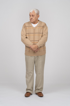 一位身穿休闲服的老人双手交叉站立，望向一旁的正面图