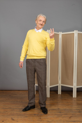 Front view of an old man showing peace-sign