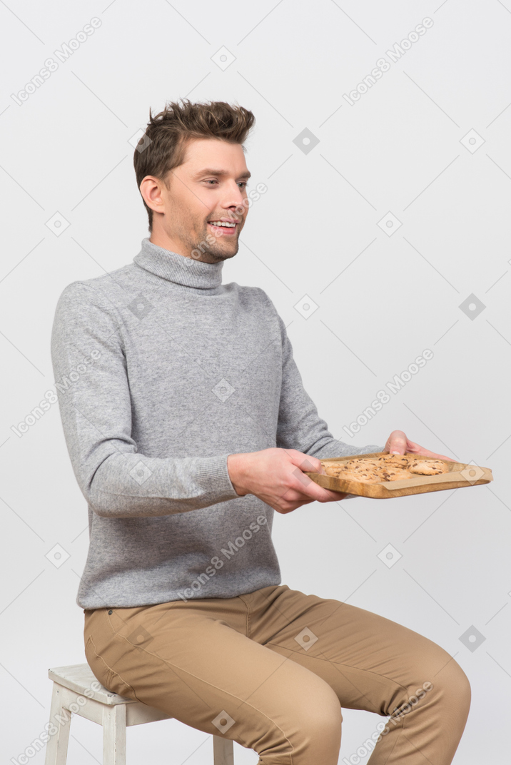 Young man holding a tray with oatmeal cookies