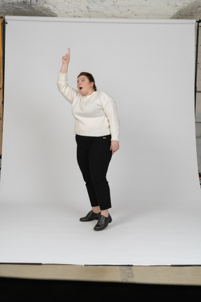 Front view of a plus size woman in casual clothes standing with raised arm