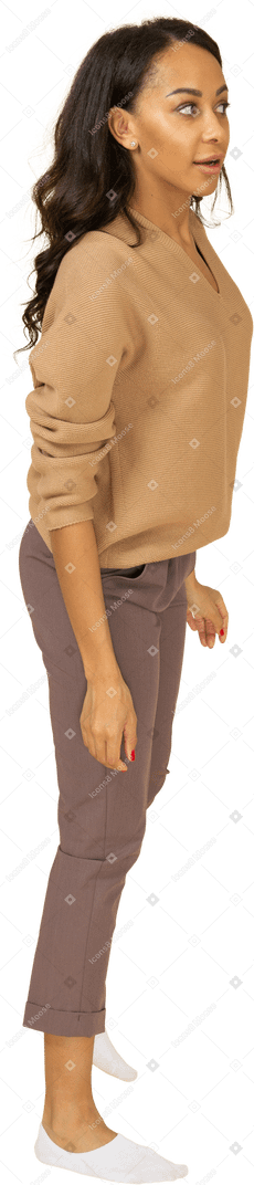 Vue latérale d'une curieuse jeune femme à la peau sombre s'appuyant sur sa jambe