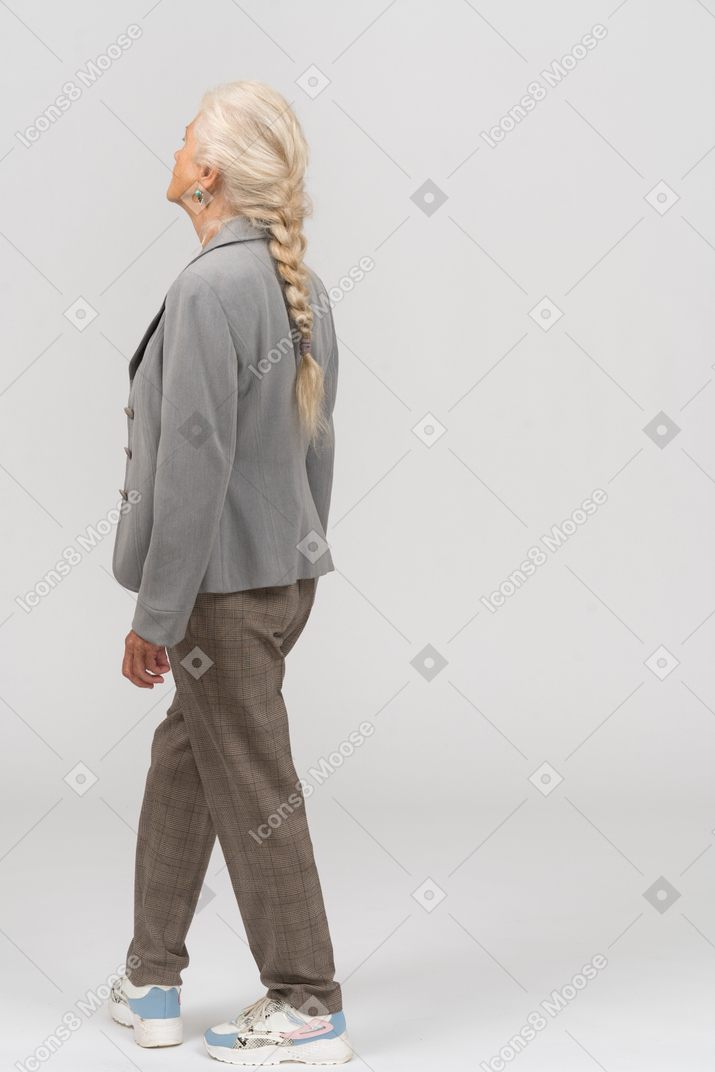 Side view of an old lady in suit standing with crossed legs