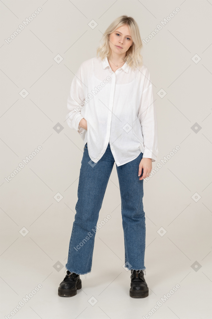 Front view of a blonde female in casual clothes putting hand in pocket and looking at camera