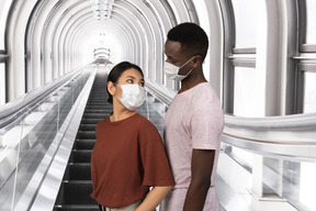 A woman and a man wearing face masks on an escalator