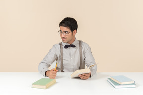 Profesor sentado a la mesa y leyendo libros