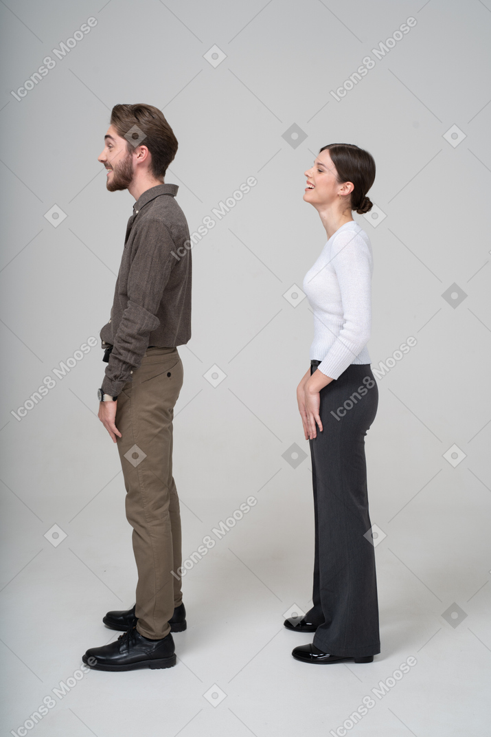 Vue latérale d'un jeune couple en riant en vêtements de bureau