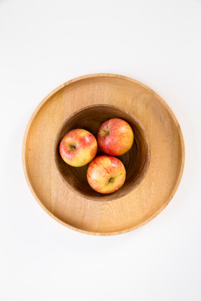 Apples in wooden plate on some plates