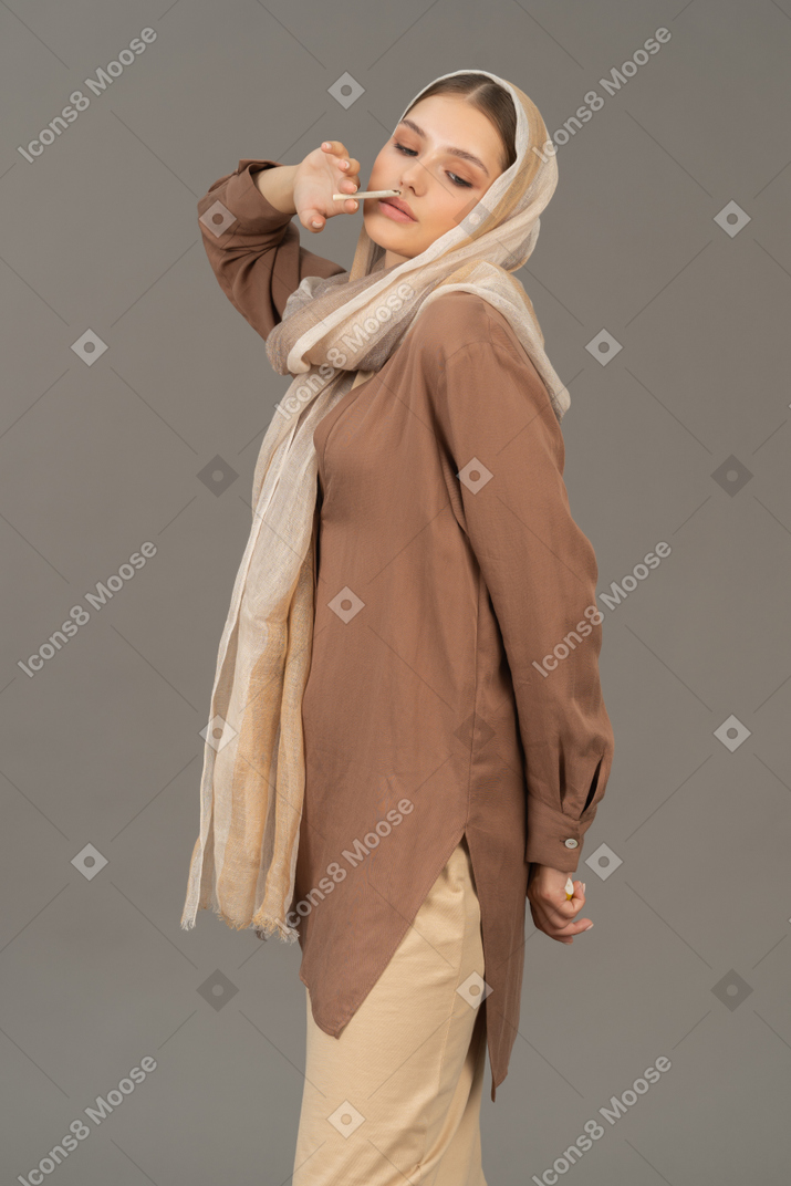 タバコを持っているベージュの服の若い女性