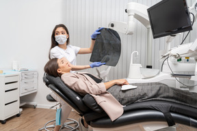 Longitud total de una mujer dentista perturbada y su paciente mirando rayos x