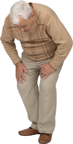 Front view of an old man in casual clothes bending down