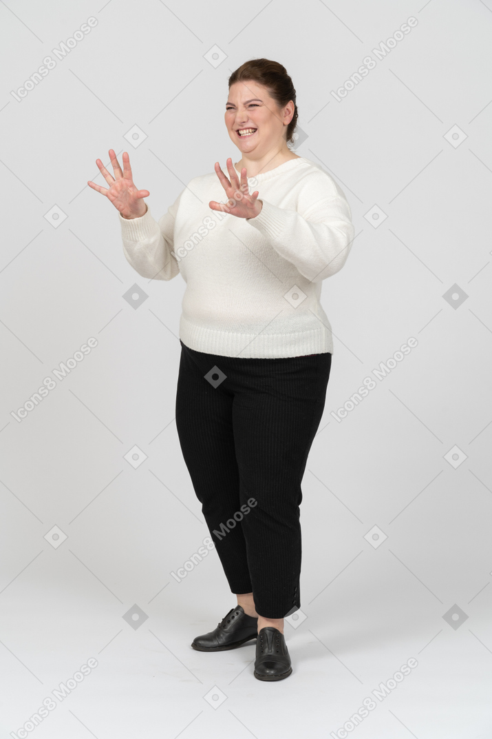 Счастливая пухлая женщина в белом свитере корчит рожи