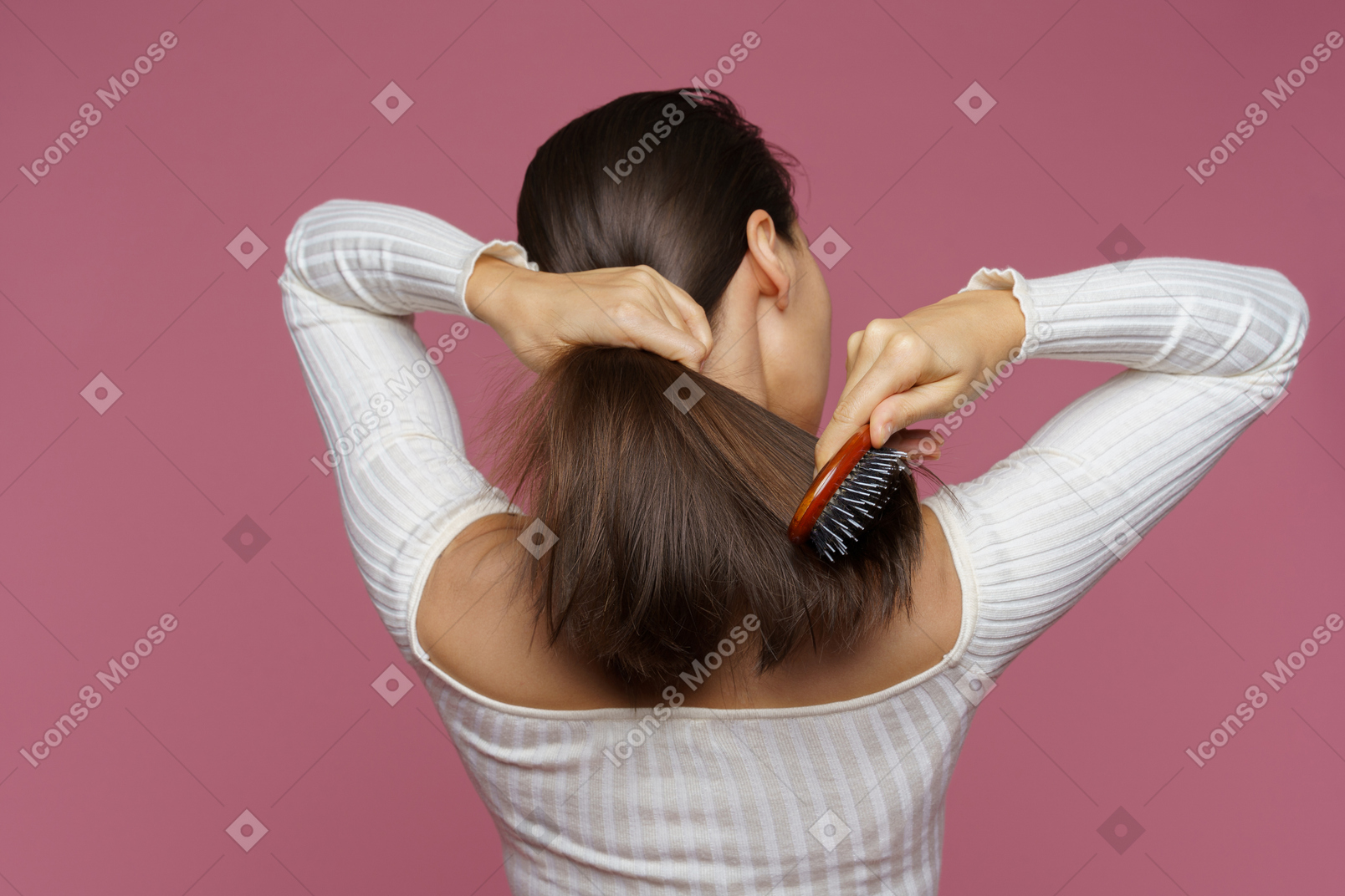 Vista posterior de una mujer de cabello castaño peinándose