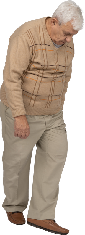 Vista frontal de un anciano con ropa informal caminando y mirando hacia abajo