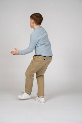Back view of a young boy in a blue shirt playing tag