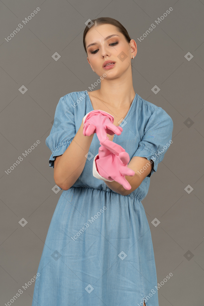 Portrait of a young woman taking off pink latex gloves