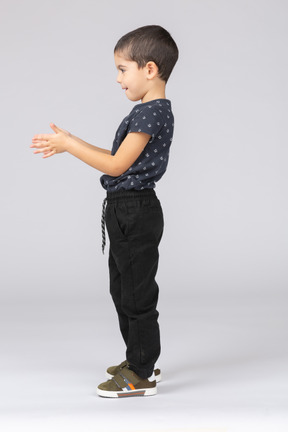Vista lateral de um lindo menino posando com os braços estendidos