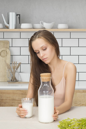 A woman sitting at a table with a bottle of milk