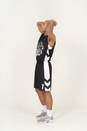 Side view of a surprised young male basketball player touching head