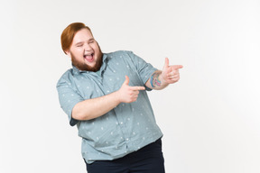 Laughing young overweight man pointing forward