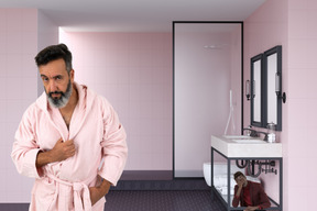 A man in a pink robe standing in a bathroom