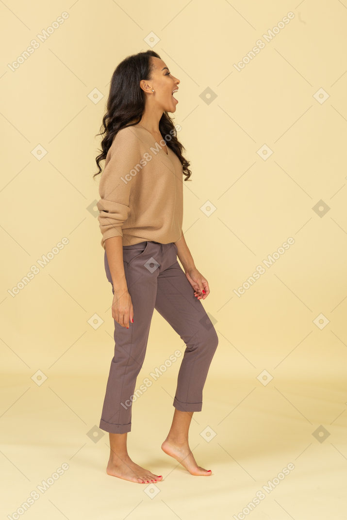 Vista lateral de una mujer joven de piel oscura riendo