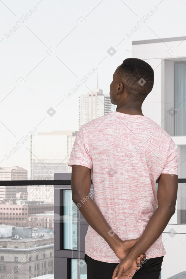 A man standing at a balcony and looking out at a city