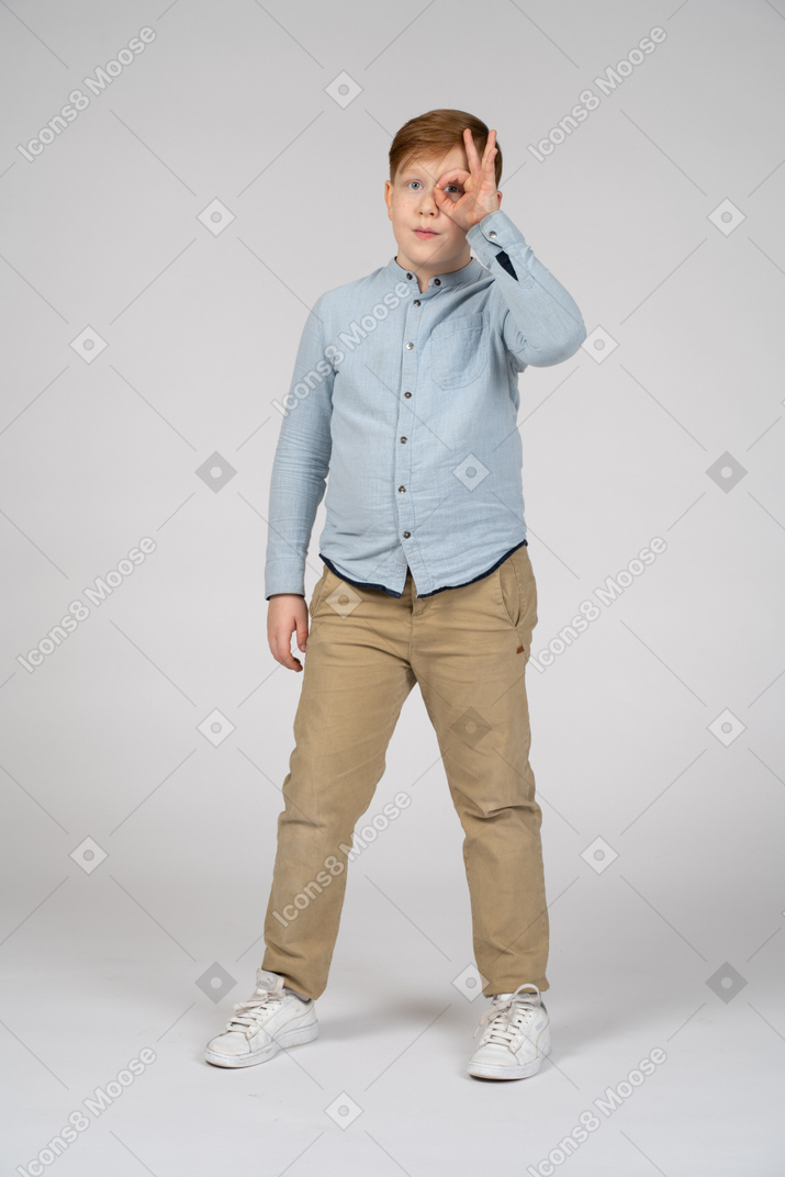 Vista frontal de un niño mirando a la cámara a través de un binocular imaginario