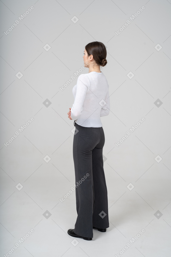 Mujer joven en pantalón negro y blusa blanca posando de perfil