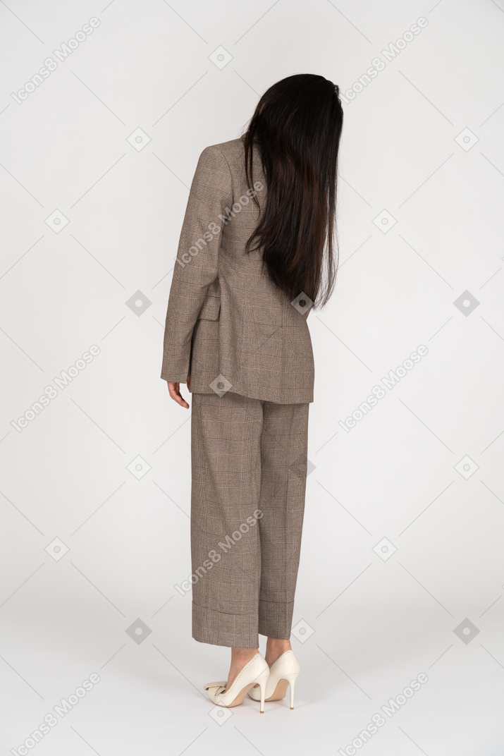 Three-quarter back view of a young lady in brown business suit tilting head